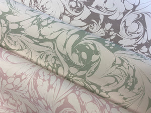 Flourish wallpaper by House of Amitié in green, partly unrolled roll showing flowing scrolls