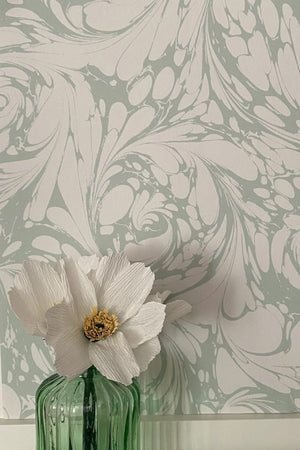 Flourish wallpaper by House of Amitié in green, flowing scrolls in a styled room setting