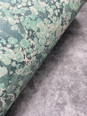 Ditzy wallpaper by House of Amitié in green, partly unrolled roll showing fine hand-marbled pattern