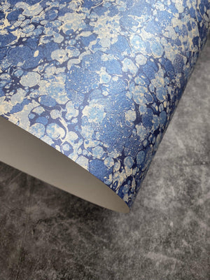 Ditzy wallpaper by House of Amitié in blue, partly unrolled roll showing fine hand-marbled pattern