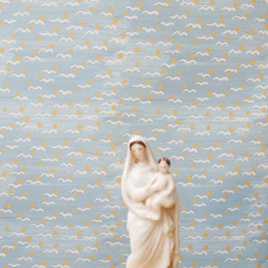 Malo wallpaper by Claire de Quénetain in yellow, scattered tiny motifs above a sideboard