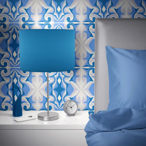 Marco Island wallpaper by Liberty James Studio in blue, a scrolling damask design behind a sofa in a living room