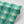 Motif wallpaper by Tatie Lou in green, partly unrolled roll showing geometric pyramids