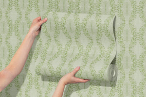 Clover Garden grasscloth by Dami and Em Design in light green, a panel unrolled showing a trailing clover motif