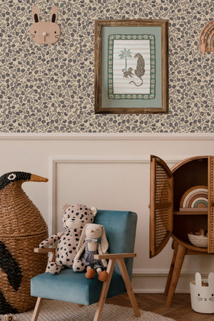Annabelle wallpaper by Curate Space in charcoal grey, ditsy hand-painted florals in a nursery with a wicker chair and a teal armchair