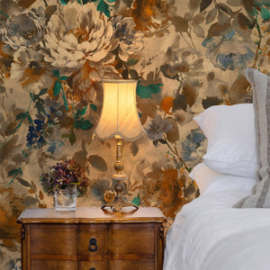Bridie wallpaper by Curate Space in warm autumn orange, oversized painterly blooms in a bedroom with a wooden bedside chest and table lamp
