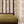 Edie wallpaper by Curate Space in ochre yellow, arching fern fronds in vertical columns behind a spindle chair with a green cushion