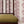 Edie wallpaper by Curate Space in red, arching fern fronds in vertical columns behind a spindle chair with a green cushion