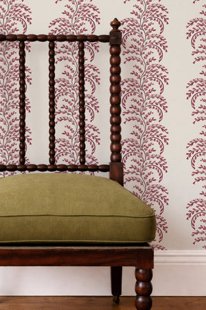 Edie wallpaper by Curate Space in red, arching fern fronds in vertical columns behind a spindle chair with a green cushion