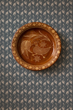 Etta wallpaper by Curate Space in dark blue, small floral sprigs behind a round decorative plate on the wall