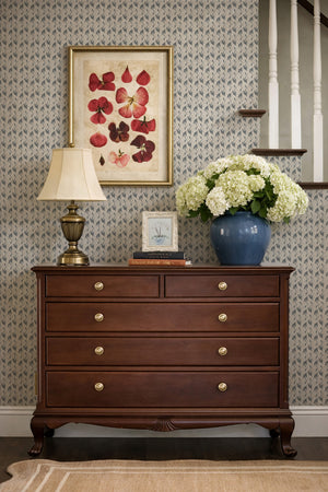 Etta wallpaper by Curate Space in navy, small floral sprigs behind a wooden chest of drawers on a staircase landing