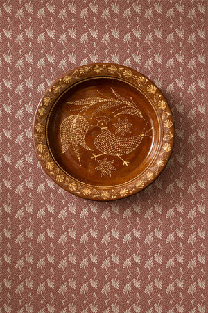 Etta wallpaper by Curate Space in red, small floral sprigs behind a round decorative plate on the wall