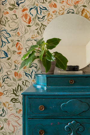 Eva wallpaper by Curate Space in off-white, a large-scale painterly floral in a room with a teal chest and a round mirror