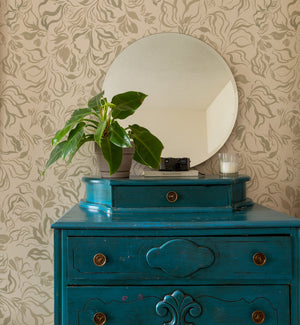 Eva wallpaper by Curate Space in soft green, a large-scale painterly floral behind a teal chest of drawers and round mirror