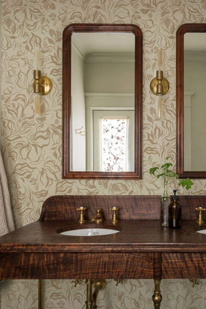Eva wallpaper by Curate Space in soft green, a large-scale painterly floral in a bathroom with a vanity and two wood-framed mirrors