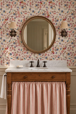 Little Freya wallpaper by Curate Space in soft pink, small abstract flowers and leaves in a bathroom with a round mirror and a wooden vanity