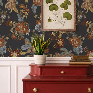 Lottie wallpaper by Curate Space in midnight blue, oversized chintz-style florals in a room with a red chest of drawers and a botanical print