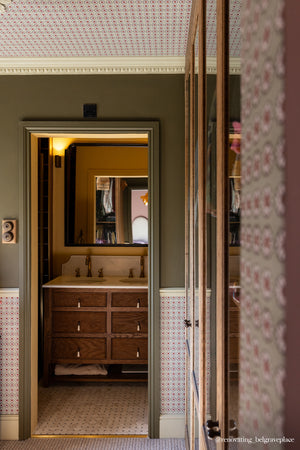 Mabel wallpaper by Curate Space in moss green, small rosette motifs in a hallway leading to a bathroom