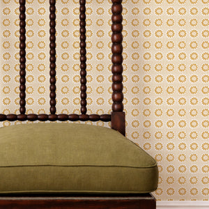 Mabel wallpaper by Curate Space in yellow, small rosette motifs behind a spindle chair with a green cushion