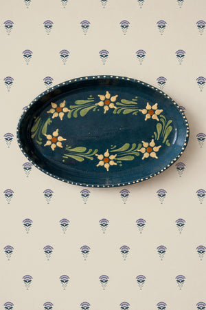 Madeline wallpaper by Curate Space in indigo, fan-shaped floral motifs behind a decorative plate hung on the wall