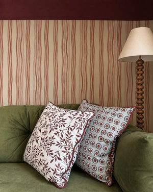 Mara wallpaper by Curate Space in red, hand-painted wavy stripes in a living room with a green sofa