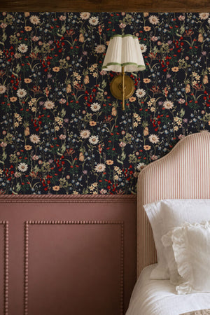 Nola wallpaper by Curate Space in midnight blue, wildflowers and tall stems in a bedroom with a brass wall sconce