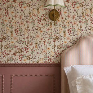 Nola wallpaper by Curate Space in off-white, wildflowers and tall stems in a bedroom with pink panelling and a brass wall sconce