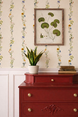 Olive wallpaper by Curate Space in light cream, vertical stripes of botanical stems and wildflowers behind a red chest of drawers and framed botanical print