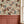 Orla wallpaper by Curate Space in light cream, layered florals and foliage over a trellis above terracotta panelling beside a window