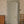 Paloma Curate Space wallpaper in off-white, trailing floral stems in a hallway with a grey-green door and a wooden chest