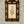 Paloma wallpaper by Curate Space in soft green, close-up of trailing floral stems behind a decorative inlaid mirror