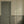 Rosalie wallpaper by Curate Space in soft green, a scalloped stripe in a hallway with a green panelled door