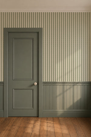 Rosalie wallpaper by Curate Space in soft green, a scalloped stripe in a hallway with a green panelled door