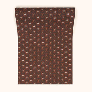 Folly wallpaper by Parker and Jules in brown, partly unrolled roll showing small sunburst medallions