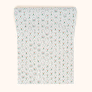 Folly wallpaper by Parker and Jules in pale green, partly unrolled roll showing small sunburst medallions