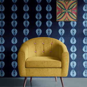 Indigo Nui wallpaper by Tatie Lou in indigo blue, nui shibori dots behind a sofa in a living room