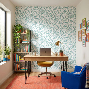 Pia wallpaper by Claire de Quénetain in light green, scattered leaves behind a desk in a home office